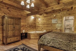 A wooden cabin interior with a bed, a cabinet, a bathroom with a bathtub, and a sign indicating the sale of pumpkins, apple cider, and hayrides.