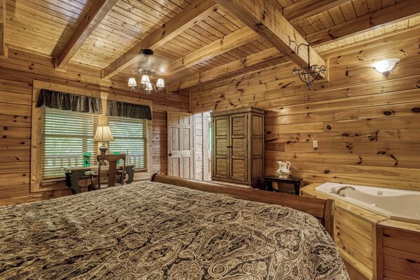 A wooden cabin interior with a bed, a desk, a cabinet, and a bathtub.