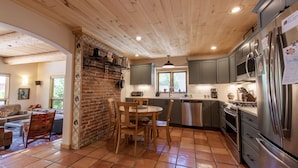 A kitchen with wooden ceiling, grey cabinets, stainless steel appliances, and a brick wall. - Le Petit Soliel - In-Town Home, Ready for Your Whole Family! (Salida)