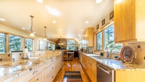 A spacious kitchen with wooden cabinets, granite countertops, and a central island. - Fox Haven at Summerwood Neighborhood, Community Pool+Clubhouse, Private Decks (Dillon)
