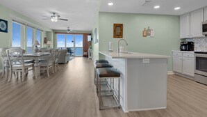 Une cuisine spacieuse dotée d’un îlot central, d’un coin repas avec vue et d’un ventilateur de plafond.