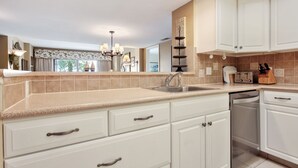 A modern kitchen with white cabinets, a stainless steel dishwasher, and a countertop with a built-in toaster.