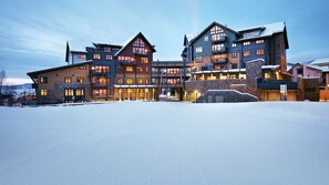 Un grande hotel a più piani con un design architettonico moderno, caratterizzato da una facciata in pietra e numerosi balconi.