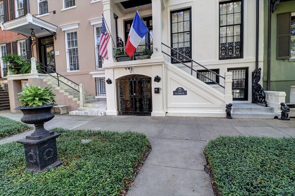 A building with a grand entrance, a staircase, and two flags.
