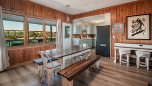A wooden-paneled room with a dining table, benches, and a kitchen area.