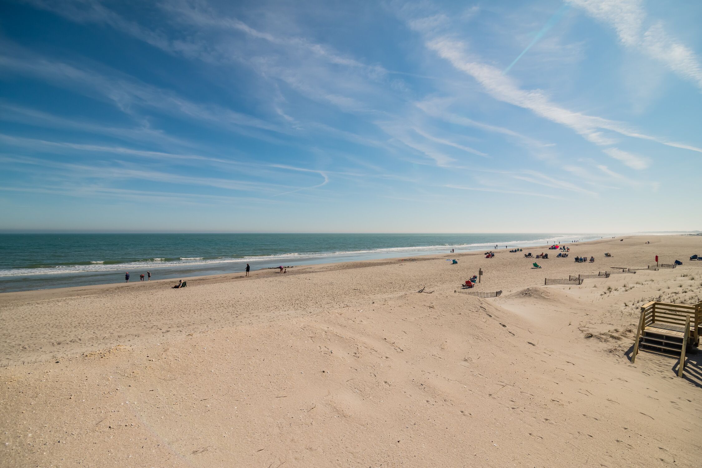 A wide sandy beach with a clear sky and ocean.