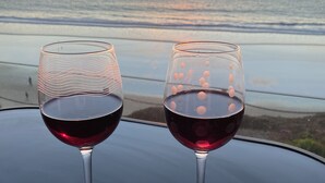 Two wine glasses on a table with a sunset view over the ocean.