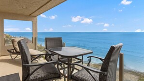 A terrace with wicker furniture overlooking a beach.