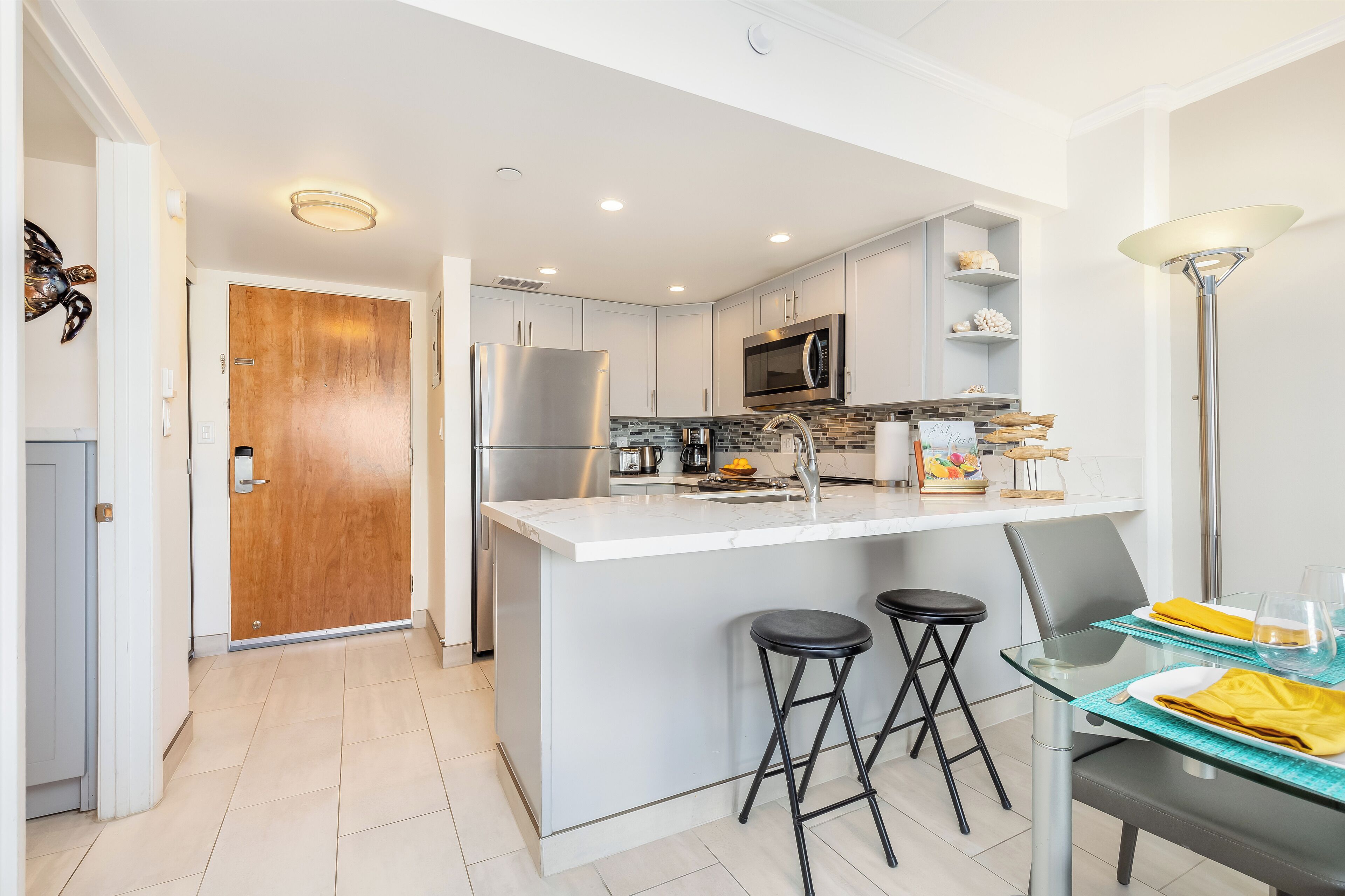 Una cocina moderna con una isla central, electrodomésticos de acero inoxidable y un área de comedor con taburetes.