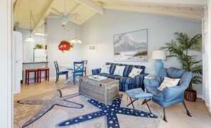 Un salon comprenant un canapé, des fauteuils, une table basse et un tapis orné d’un motif en forme d’étoile de mer.