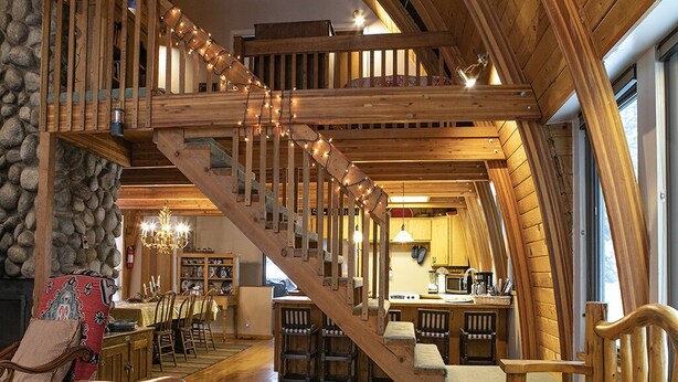 A spacious loft with a wooden staircase, a dining area, and a kitchen. - Blanche's Retreat by Cottonwood Lodging (Brighton)