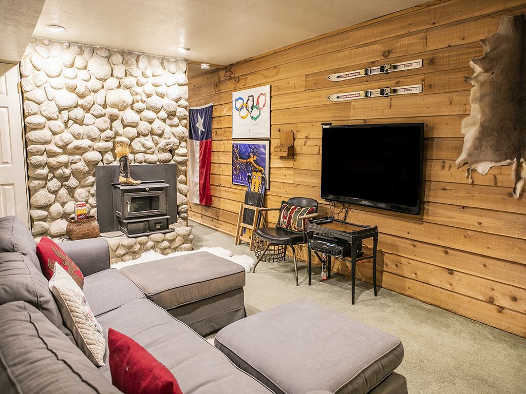 A cozy living room with a stone wall, a fireplace, a television, and a couch.