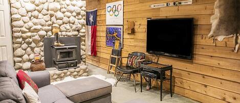 A cozy living room with a stone wall, a fireplace, a television, and a couch.