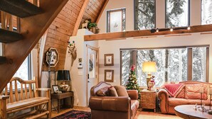 A cozy living room with a wooden staircase, leather sofas, a coffee table, and a Christmas tree. - Blanche's Retreat by Cottonwood Lodging (Brighton)
