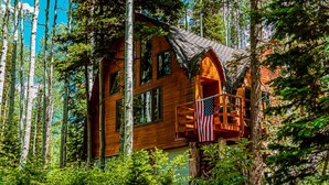 A wooden cabin with a balcony, surrounded by trees. - Blanche's Retreat by Cottonwood Lodging (Brighton)
