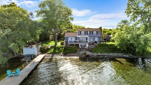 Une maison avec un quai s’avançant dans une étendue d’eau calme, entourée d’une végétation luxuriante.
