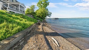 Une propriété située au bord de l’eau, dotée d’une terrasse couverte, d’une pelouse et offrant une vue dégagée sur l’eau.