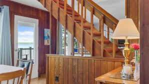 Un intérieur en bois avec un escalier, un coin repas et une vue sur l’extérieur.