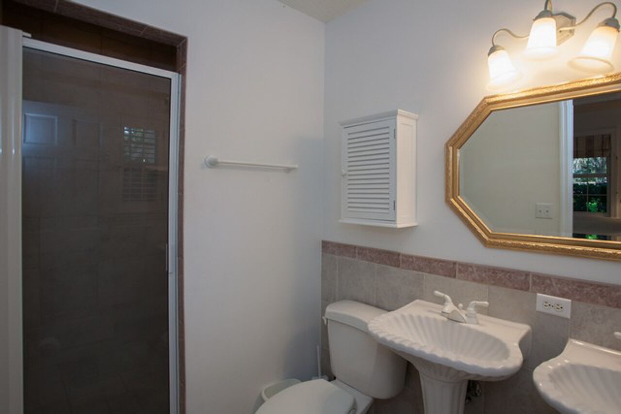 Un baño con ducha, inodoro y dos lavamanos.