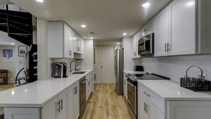 Een moderne keuken met witte kasten, roestvrijstalen apparatuur en een houten vloer.