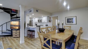 Een moderne keuken met witte kasten, een centraal eiland en een eethoek met houten stoelen en een tafel.