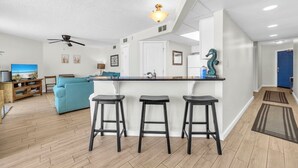 Una cocina moderna con barra, piso de madera y ventilador de techo.
