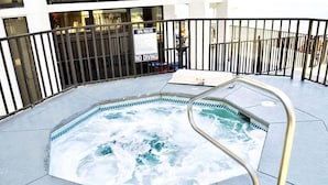 Un jacuzzi con escalera metálica, rodeado por una cerca de metal negro, y un cartel que indica 'SPA RULES NO DIVING'.
