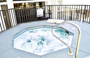 A hot tub with a metal ladder, surrounded by a black metal fence, and a sign indicating 'SPA RULES NO DIVING'.