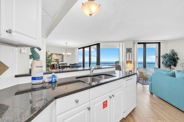 A modern kitchen with a large island, a dining area with a view, and a balcony with a view.