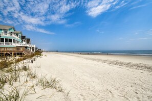 A beach with a row of houses and a pier extending into the ocean.