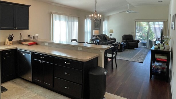 A modern kitchen with a large island, dark cabinetry, and a dining area with a sofa and chairs.