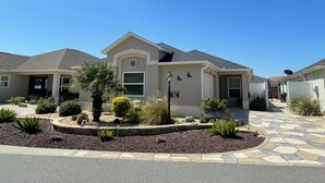 A residential house with a landscaped front yard, a driveway, and a satellite dish.