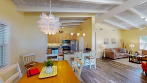 Een moderne keuken met houten kasten, een centraal eiland en een eethoek met een houten tafel en stoelen.