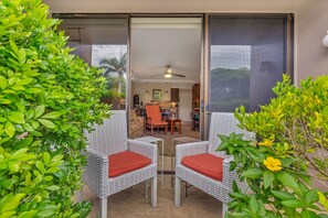 Un patio con sedie in vimini e una porta scorrevole in vetro che dà su un angolo cucina.