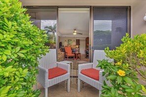 A patio with wicker chairs and a sliding glass door leading to a kitchen area.