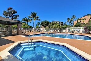 A swimming pool area with lounge chairs and a covered seating area.