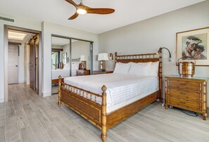 A spacious bedroom with a large wooden bed, a nightstand, a dresser, and a ceiling fan.