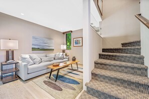 Una sala de estar moderna con un sofá, una mesa de centro y una escalera.