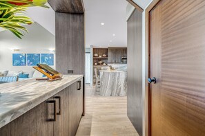 A modern kitchen with a marble countertop, wooden cabinets, and a central island.