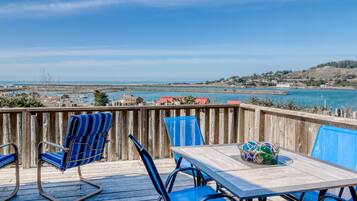 Enjoy the serene coastal view from this outdoor deck, featuring a table and comfortable seating.