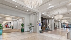 Un hall d’entrée spacieux, doté d’un comptoir de réception, de plantes en pot et de lustres modernes.