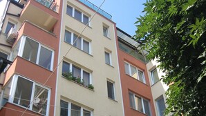 Un immeuble résidentiel à plusieurs étages, doté de balcons, de grandes fenêtres et d’un arbre au premier plan.