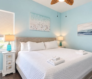 Slip into comfort in this serene coastal bedroom, where soft ocean hues and fresh linens welcome you. Drift off beneath the tropical ceiling fan and wake to gentle seaside light.