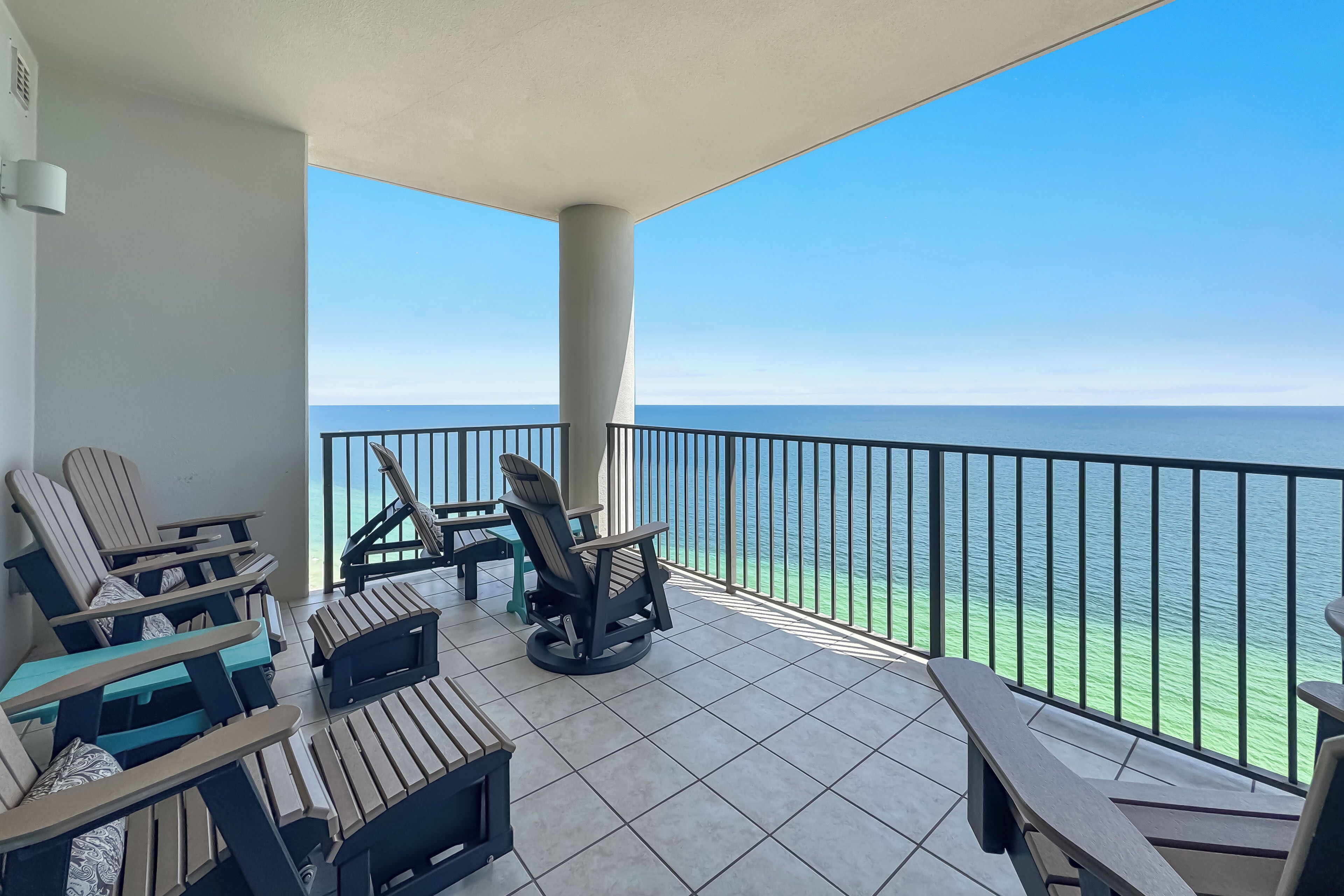 A balcony with a view of the ocean, furnished with chairs and a table.