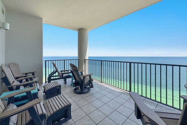 A balcony with a view of the ocean, furnished with chairs and a table.