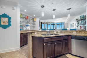 A modern kitchen with granite countertops, dark wood cabinets, and a built-in dishwasher.