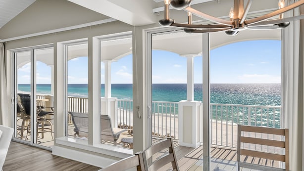 A spacious balcony with a view of the ocean, furnished with chairs and a table.