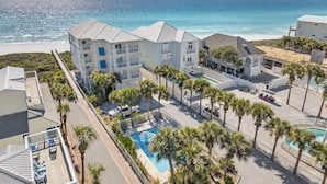 A beachfront hotel with multiple buildings, a swimming pool, and palm trees.