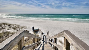 A wooden staircase leading to a beach with a clear view of the ocean.