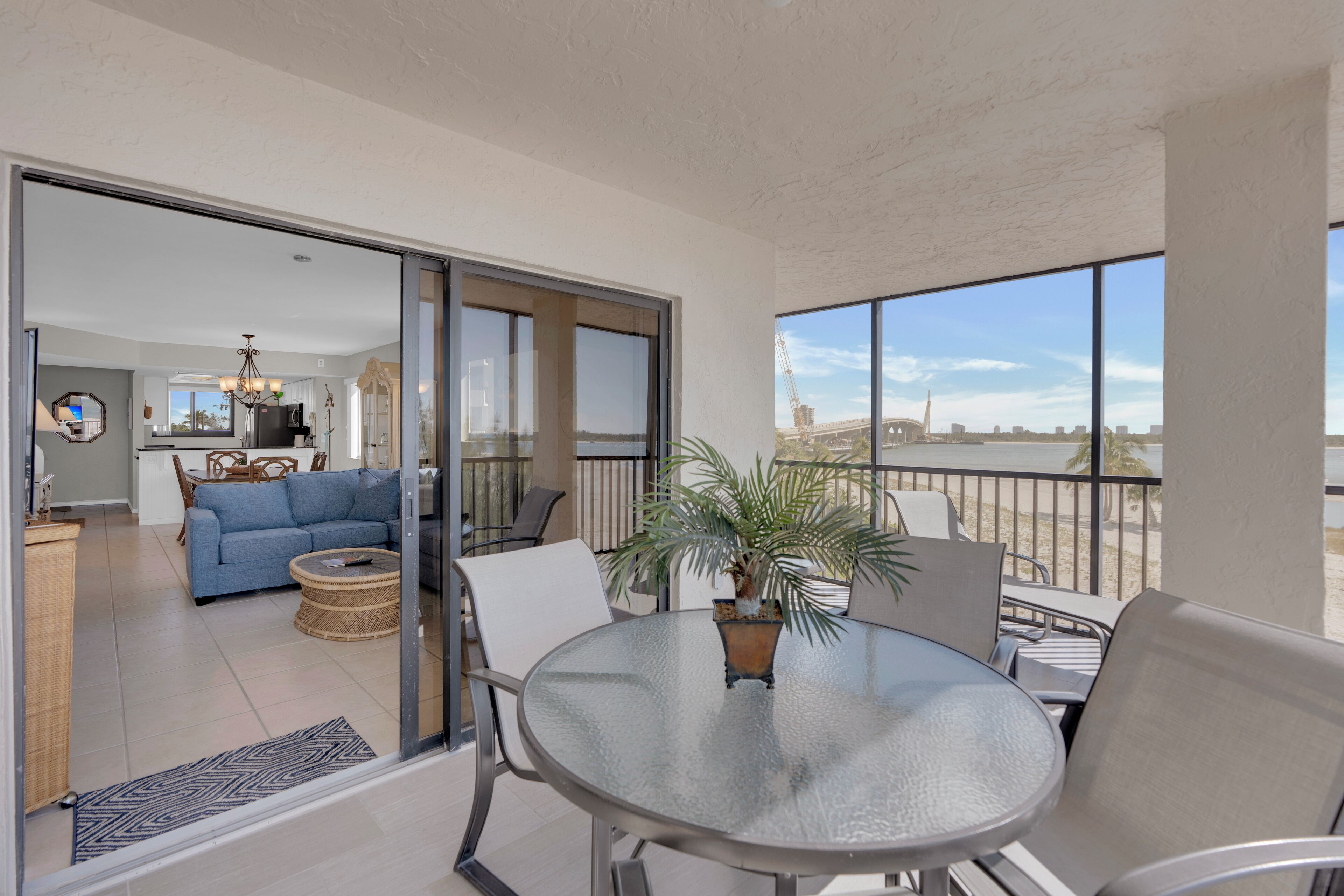 Een balkon met een glazen tafel en stoelen, een bloempot en uitzicht op de skyline van de stad.